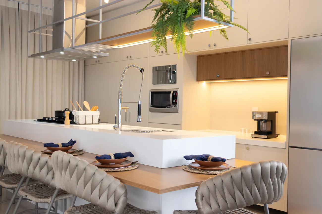 Cozinha com ilha, banquetas estofadas e torre de eletrodomésticos